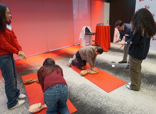 Several girls receiving instruction in hands only CPR